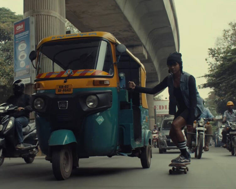 Indian skate culture woman riding on skateboard while holding on tuk tuk