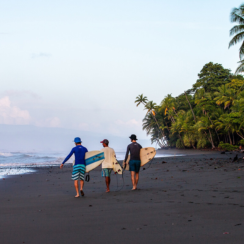 Guests of Mokum Surf Club Costa Rica retreat walking on the beach with their surf coach