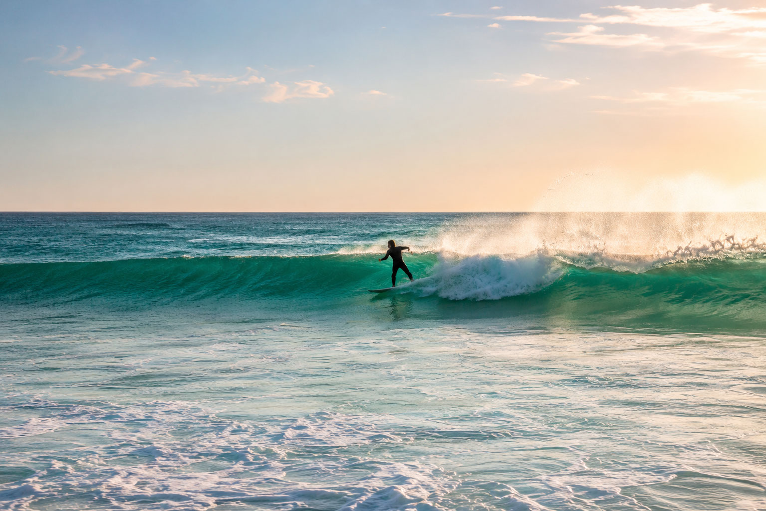 Surfer riding a clean wave at golden hour on the Atlantic coast of Portugal.